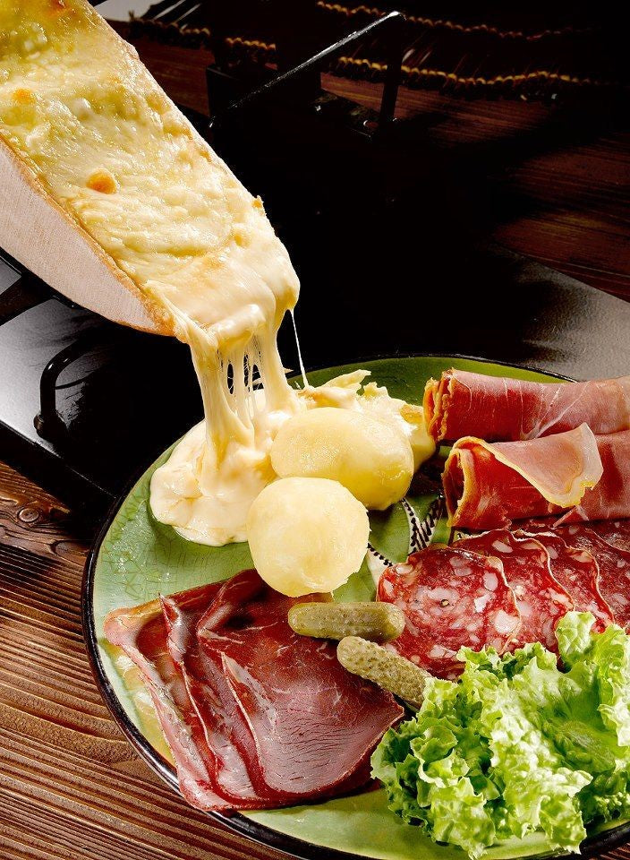 The name of this cheese is derived from the word racler, meaning ‘to scrape’, which describes the way that the cheese is traditionally prepared and eaten. The wheel of cheese is cut and heated and the melted cheese can then be scraped from the wheel with a knife. Raclette is traditionally accompanied by boiled potatoes, cured meats and pickles, flavours which match well with the cheese’s fruity, slightly mouldy aroma and full, savoury flavour.
