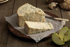 Gorgonzola dolce mild creamy blue cheese on a wooden board with a knife and a green apples
