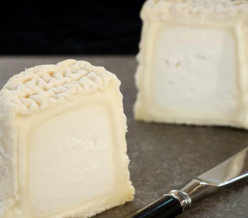 This particular cheese has a thin wrinkled white rind when young, with a blue-grey mould forming over parts of the rind and later a reddish growth may develop. The interior is firm and snow white and will become drier with age.